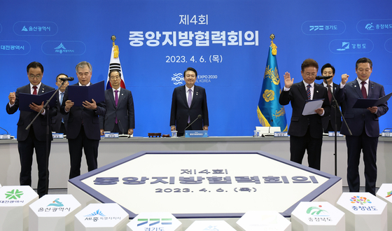 President Yoon Suk Yeol, center, watches as the heads of the Governors Association of the Republic of Korea, the National Association of Mayors in Korea, the Metropolitan, Provincial Council Chairs Association and the National Association of Local Council Chairmen read out a joint resolution pledging support from local leaders for Busan’s World Expo 2030 bid ahead of a meeting on regional cooperation at Bexco in Busan on Thursday. [JOINT PRESS CORPS]