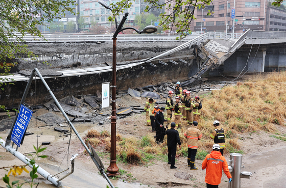Officials comb the area of Jeongja Bridge in the Bundang District of Seongnam, Gyeonggi on Wednesday after the structure collapsed that morning, killing one and seriously injuring another. [YONHAP]