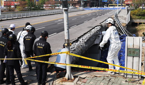Police and National Forensic Service investigators conduct a site inspection of the collapsed walkway of Jeongja Bridge in Seongnam's Bundang District on Friday. [YONHAP]