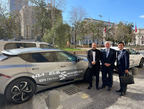 Hyundai Motor Group promotes Busan's bid for the 2030 World Expo using its global network of retailers across the world. Former Director of Informatics and Communications of the Ministry of Foreign Affairs of Chile Patricio Powell at center, poses with Kia representatives and a Kia car decorated with the 2030 World Expo Busan logo in front of Chile's Foreign Affairs Ministry building in Santiago on Sept. 21, 2022. [HYUNDAI MOTOR GROUP]