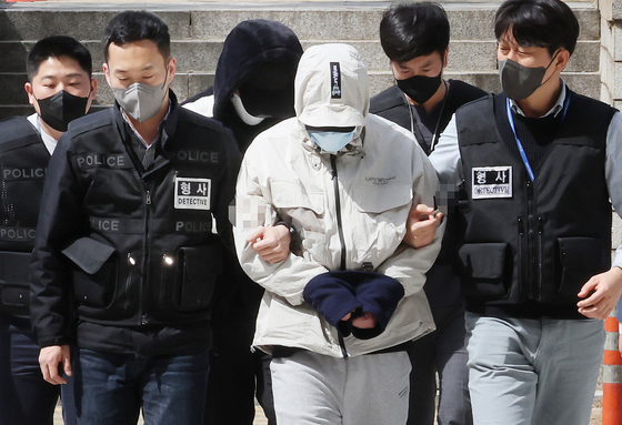 A suspect surnamed Kim, in white, who was in charge of blackmailing the parents of students who consumed drug drinks, enters the Seoul Central District Court in southern Seoul on Monday. [YONHAP]