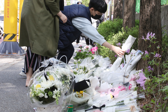 A child places a flower on a memorial set up in Daejeon for Bae Seung-ah, a 9 year old who was killed by a drunk driver on the weekend. [YONHAP]