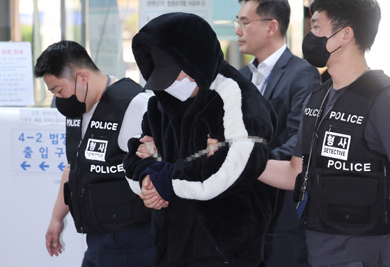 A local middleman surnamed Gil, center, who was in charge of making drinks containing drugs to give out to students, enters the Seoul Central District Court on Monday. [YONHAP]