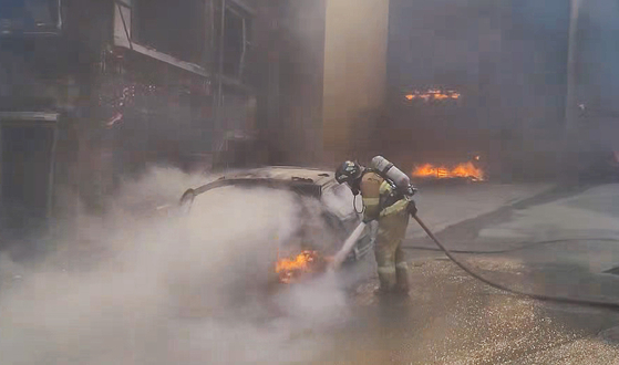 A firefighter putting out a fire that caught on a vehicle in Gangneung, Gangwon on Tuesday. [NATIOAL FIRE AGENCY] 