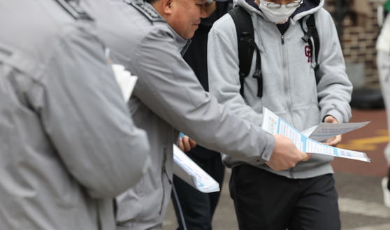 Police officers distribute pamphlets on drug-related precautions to students at the entrance of Garak High School in Songpa District, southern Seoul, on Tuesday. Seoul Metropolitan Police Agency issued an emergency news alert to 1,407 elementary, middle and high schools and 830,000 parents in the city, providing guidance on reporting and investigating drug crimes. [YONHAP]