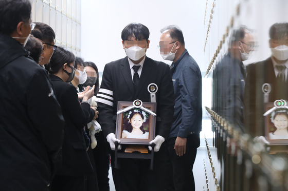 The brother of Bae Seung-ah carries a picture of the 9 year old as her coffin was carried out of the Eulji Medical Center in Daejeon, Tuesday. [YONHAP]