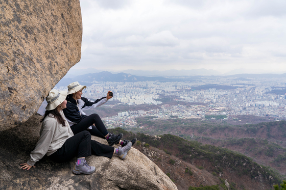 Young hikers take pictures on Yeongbong Peak at Mount Bukhan in Seoul. [BAEK JONG-HYUN]