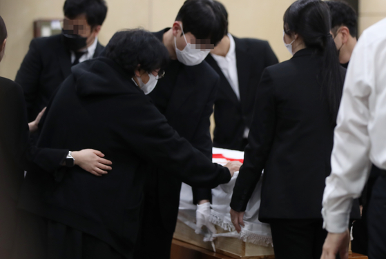 The bereaved mother lays her hand on the coffin where her 9-year-old daughter Bae Seung-ah lies at the funeral home at Eulji Medical Center in Daejeon on Tuesday. The 9-year-old was killed by a drunk driver who hit three other children walking on the sidewalk near an elementary school. The speed limit near schools is 30 kilometer per hour. This is the second drunk driving incident that killed a child in the last four months. The last was in December, when a 39-year-old taxi company owner ran over another 9-year-old near a school in Gangnam, Seoul. [YONHAP]
