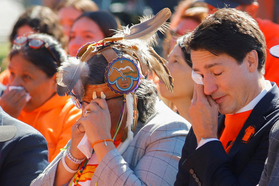 Canada's Prime Minister Justin Trudeau and Assembly of First Nations national chief RoseAnne Archibald wipe tears as they take part in the National Day for Truth and Reconciliation, honouring the lost children and survivors of Indigenous residential schools, during an event at Lebreton Flats in Ottawa, Ontario, Canada, Sept. 30, 2022. [REUTERS/YONHAP] 