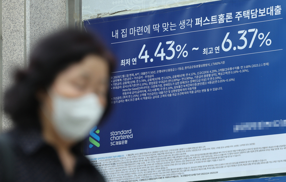 A person walks past a banner promoting loans in front of a bank in Seoul on Sunday. With banks cutting the mortgage rate, the average rate at the country's four commercial banks — KB Kookmin, Shinhan, Woori and Hana — stood at between 3.6 percent and 5.8 percent as of April 14, down 0.77 percentage point compared to a month ago. [YONHAP]