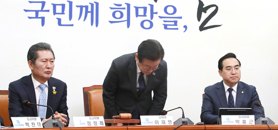 Democratic Party (DP) Chairman Lee Jae-myung, center, bows his head in apology over mass bribery allegations against DP members and lawmakers during a party meeting at the National Assembly on Monday. [NEWS1]