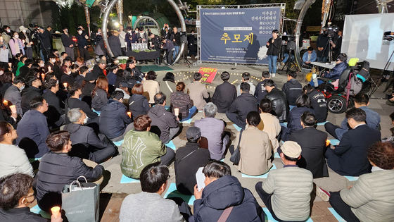 People hold a candlelight vigil in front of the subway station in Michuhol District, Incheon, late Tuesday to commemorate the victims of jeonse fraud who committed suicide. [YONHAP]
