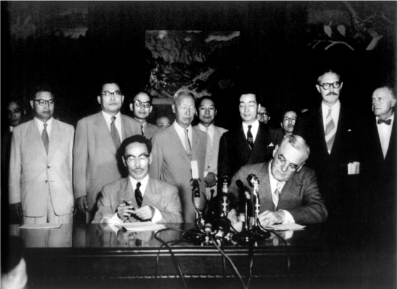 Korean President Syngman Rhee, center, watches Foreign Minister Byun Young-tae, front row left, and U.S. Secretary of State John Dulles, front row right, sign a provisional mutual defense treaty on Aug. 8, 1953 in Seoul. [JOONGANG PHOTO] 