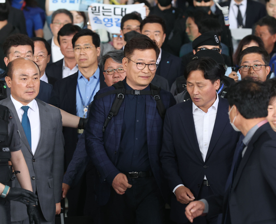 Former Democratic Party leader Song Young-gil is surrounded by reporters as he exits immigration at Incheon International Airport on Monday. [YONHAP]