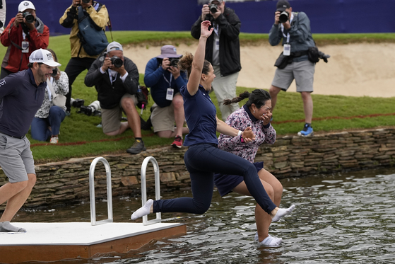 Lilia Vu, right, jumps into the lake on the 18th hole with Anne-Lise Bidou after winning the Chevron Championship at The Club at Carlton Woods in The Woordlands, Texas on Sunday. [AP] 