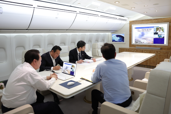  President Yoon Suk Yeol on Monday presides over a satellite-linked video meeting on Air Force One headed to the United States. [PRESIDENTIAL OFFICE] 