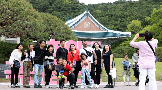 The number of visitors to the Blue House compound went up due to warm weather, the Ministry of Culture, Sports and Tourism said Wednesday. Foreign visitors pose in front of the camera at the compound on Wednesday. [YONHAP]