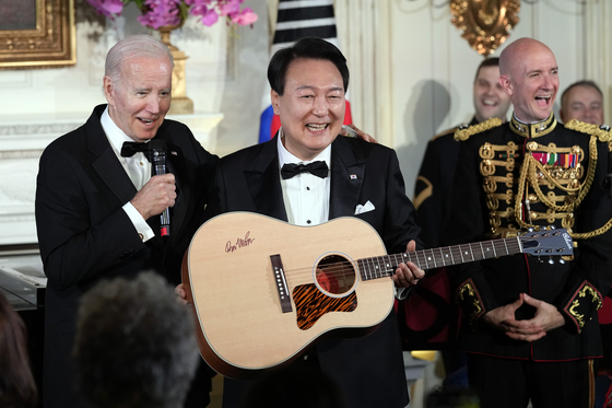 U.S. President Joe Biden, left, surprises President Yoon Suk Yeol with a guitar signed by Don McLean at the state dinner held at the White House in Washington Wednesday. [AP/YONHAP]