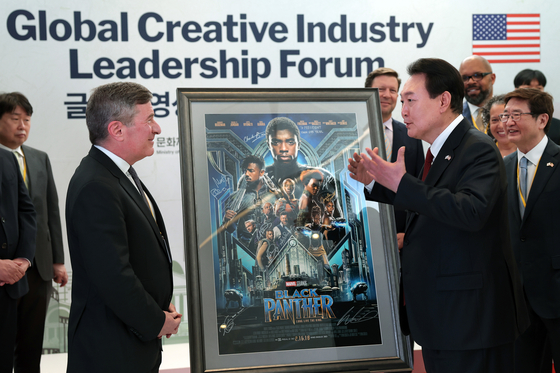 President Yoon Suk Yeol, right, receives a Black Panther film poster signed by the late Chadwick Boseman by Charles Rivkin, Motion Picture Association chairman and CEO, during a film and content forum held in Washington on Thursday. [JOINT PRESS CORPS]