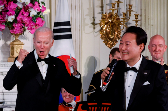 U.S. President Joe Biden, left, cheers as Korean President Yoon Suk Yeol sings at a state dinner at the White House in Washington Wednesday. [REUTERS/YONHAP]