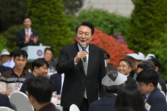 President Yoon Suk Yeol, center, speaks to the press corps at a luncheon marking the opening of the Yongsan Children's Garden later this week in a lawn in front of the presidential office in central Seoul on Tuesday afternoon. [PRESIDENTIAL OFFICE]