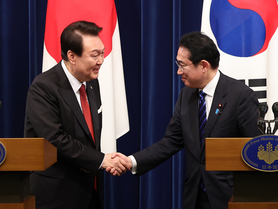 President Yoon Suk Yeol, left, shakes hands with Japanese Prime Minister Fumio Kishida at the end of their joint news conference after their summit in Tokyo on March 16. [YONHAP]