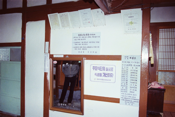 A restaurant in Dangjin, South Chungcheong, in 1983 that is charging customers for each side dishes. According to the menu on the wall, a dish of kimchi was sold for 200 won, bean sprouts for 100 won and gim, or dried seaweed, for 200 won. [WOORIDATA]