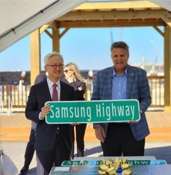 Samsung Electonics' chip CEO Kyung Kye-hyun receives a ″Samgsung Highway″ road sign from Williamson County Judge Bill Gravell at Samsung's Taylor plant construction site on Jan. 15. Kyung announced the chipmaker's plans to complete construction within the year 2023. [SCREEN CAPTURE]