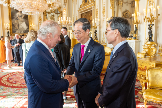 British King Charles III, left, greets Korean Prime Minister Han Duck-soo, center, during a reception at Buckingham Palace in London on Friday celebrating the coronation. [YONHAP]