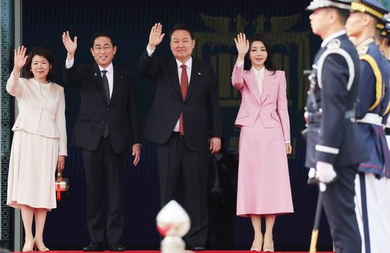 Korean President Yoon Suk Yeol, center right, and first lady Kim Keon-hee, wave with Japanese Prime Minister Fumio Kishida, center left, and first lady Yuko Kishida in a welcoming ceremony at the Yongsan presidential office in central Seoul Sunday ahead of their bilateral summit. [JOINT PRESS CORPS]