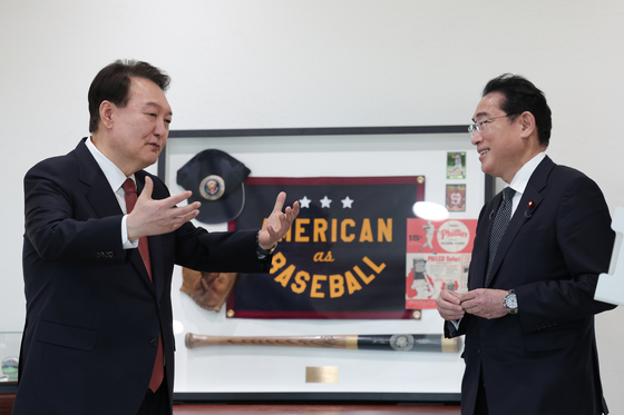 Korean President Yoon Suk Yeol, left, chats with Japanese Prime Minister Fumio Kishida, in front of U.S. President Joe Biden’s gift of baseball memorabilia from Yoon’s state visit in late April at the Yongsan presidential office in central Seoul Sunday during their bilateral summit. [PRESIDENTIAL OFFICE]