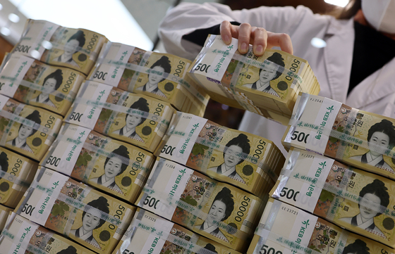 A bank employee sorts 50,000 won ($38) bills at the Hana Bank headquarters in Jung District, central Seoul, on Monday. The amount of cash flow in the Korean market decreased for two consecutive quarters for the first time in 15 years, according to the Bank of Korea. There was 174.62 trillion won in cash circulating the market in the first quarter, down 0.5 percent on quarter. [YONHAP]