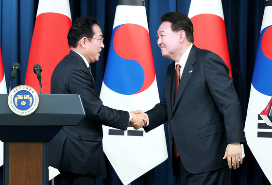 Korean President Yoon Suk Yeol, right, shakes hands with Japanese Prime Minister Fumio Kishida during their joint press conference at the Yongsan presidential office in central Seoul Sunday after their bilateral summit. [JOINT PRESS CORPS]