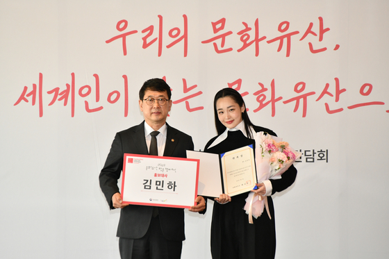 Choi Eung-chon, left, the chief of Cultural Heritage Administration and Apple TV’s hit series “Pachinko” star Kim Min-ha pose for a photograph after she was appointed as this year's PR Ambassador of the "Visit Korean Heritage Campaign" on Tuesday at the Westin Josun Hotel in central Seoul. [CHA] 