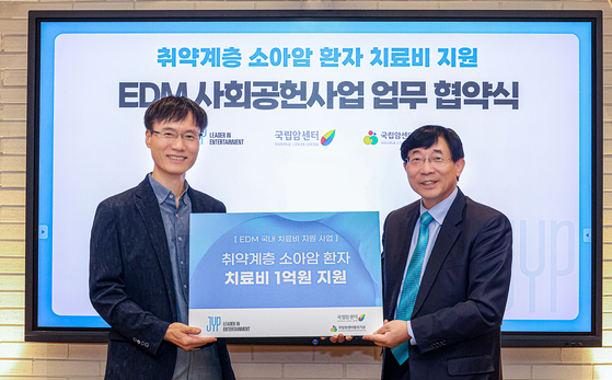 Byun Sang-bong, vice president of JYP Entertainment, left, and Seo Hong-gwan, director of the National Cancer Center Foundation pose for the camera after signing an agreement to support medical expenses of children and teenage cancer patients [JYP ENTERTAINMENT]