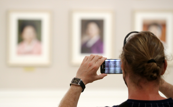 A visitor from overseas takes a picture of the first lady portraits inside the Main Office Building of the Blue House. [MINISTRY OF CULTURE, SPORTS AND TOURISM]