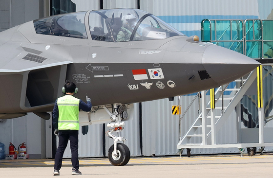 A prototype of the KF-21 fighter jet under development bearing the flags of Korea and Indonesia moves out of a hangar at the headquarters of Korea Aerospace Industries in Sacheon, South Gyeongsang, on Tuesday. [YONHAP]
