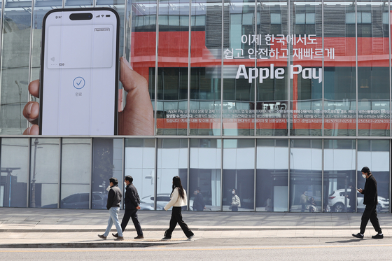 People walk past the Hyundai Card building in central Seoul on March 21, where Apple Pay is being promoted on the glass. Apple Pay was launched in Korea that day, in partnership with Hyundai Card. [YONHAP]