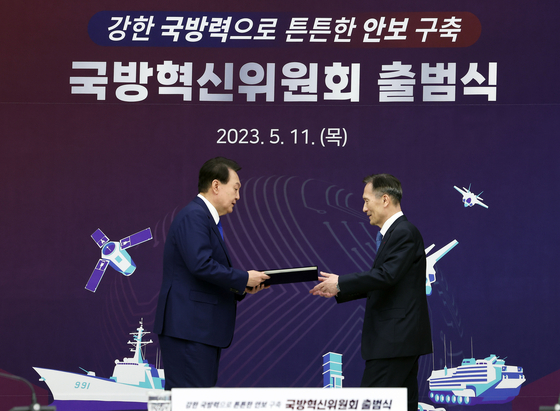 President Yoon Suk Yeol, left, presents a letter of appointment to former Defense Minister Kim Kwan-jin, who was appointed as vice chair of the new presidential Defense Innovation Committee, ahead of presiding over its inaugural meeting at the Yongsan presidential office in central Seoul on Thursday. [JOINT PRESS CORPS]