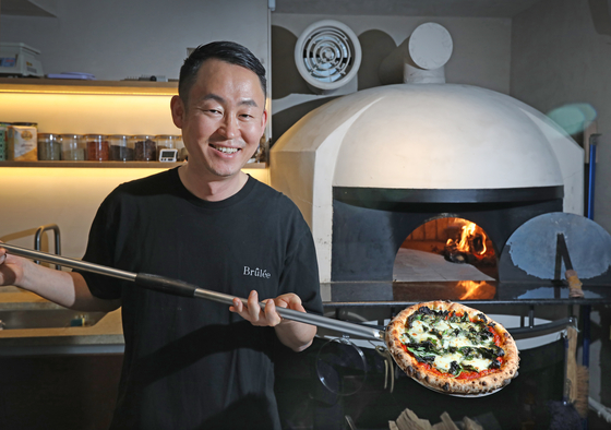 Erick Kim, owner-chef of Brûlée in Yongsan District, central Seoul, poses with a pizza made from the restaurant's woodfire oven. [PARK SANG-MOON]
