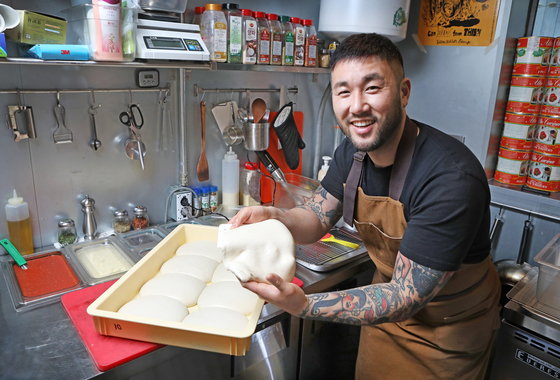 Jun Gi-hong, owner-chef of The Slice Pizza, poses with pizza dough in the kitchen of The Slice Pizza [PARK SANG-MOON]