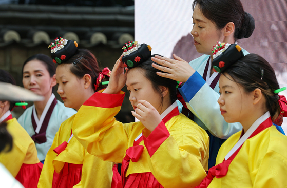 A woman fixes her jokduri, or traditional hair accessory, in a Coming of Age Day event held on the walkway outside of Deoksu Palace in central Seoul on Sunday. The event was held a day before this year's Coming of Age Day, which falls on the third Monday of May. [YONHAP] 