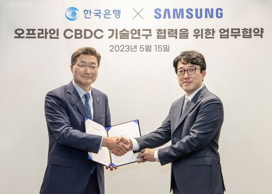 Samsung Electronics and the Bank of Korea announced on Monday that they signed a memorandum of understanding (MOU) for collaborative research on offline CBDC (Central Bank Digital Currency) technology at Samsung's headquarters in Suwon, Gyeonggi. In this photo, Bank of Korea Deputy Governor Lee Seung-heon, left, and Choi Won-joon, executive vice president and head of the mobile research and development office at Samsung’s Mobile eXperience division, pose for the camera after signing the MOU on Monday. [SAMSUNG ELECTRONICS] 