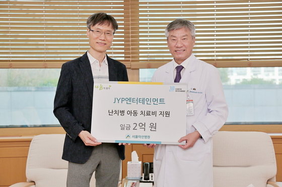 Chief financial officer of JYP Entertainment David Byun, left, poses for a photo with Asan Medical Center, after signing an agreement to donate 200 million won to the hospital to go to medical expenses for the youth. [JYP ENTERTAINMENT]