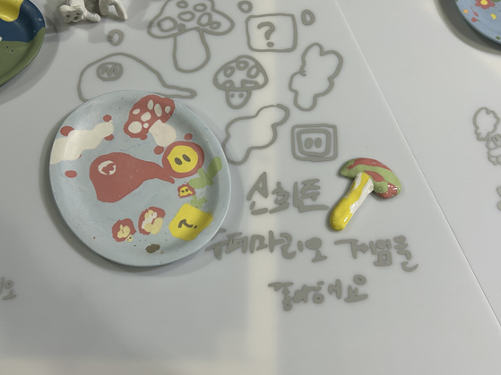 A ceramic plate made by one of 60 children for the "Twinkle Twinkle Little Hands" exhibition, as part of Korea Craft Week 2023. The description reads, "I like Super Mario games." [SHIN MIN-HEE]
