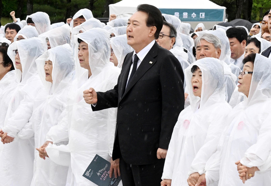 President Yoon Suk Yeol, center, sings the song ″March for the Beloved″ alongside a group of mothers of victims of the 1980 pro-democracy uprising in a ceremony marking the 43rd anniversary of the May 18 Democratization Movement at the national cemetery in Gwangju on Thursday. [JOINT PRESS CORPS]