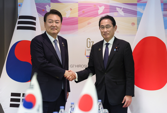 Korean President Yoon Suk Yeol, left, and Japanese Prime Minister Fumio Kishida shake hands before their bilateral summit on the sidelines of the G7 Summit in Hiroshima on Sunday. [JOINT PRESS CORPS]