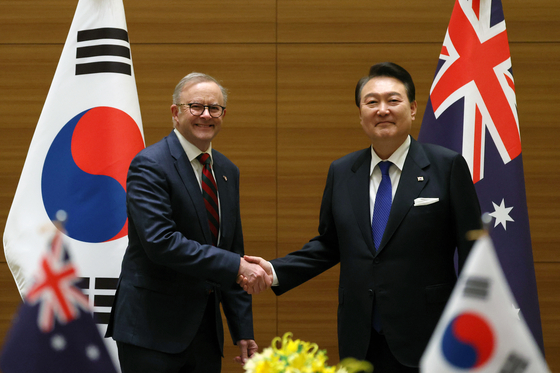 Korean President Yoon Suk Yeol, right, shakes hands with Australian Prime Minister Anthony Albanese during a bilateral summit at a hotel in Hiroshima, Japan, on Friday. [JOINT PRESS CORPS]
