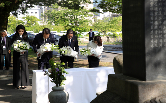 Korean President Yoon Suk Yeol, center left, and Japanese Prime Minister Fumio Kishida, center right, accompanied by first ladies Kim Keon-hee, left, and Yuko Kishida, right, bow their heads as they pay respects in front of a cenotaph for Korean victims of the 1945 Hiroshima atomic bombing at the Hiroshima Peace Memorial Park in Japan on Sunday. [JOINT PRESS CORPS]