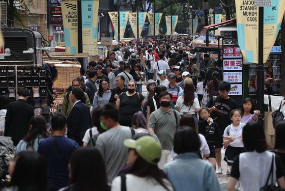 A street in Myeong-dong bustles with visitors on Sunday. [YONHAP]